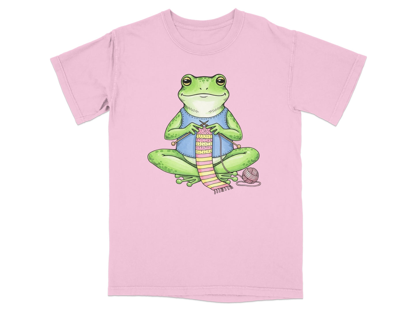 Pink t-shirt with illustration of a frog knitting a striped scarf.