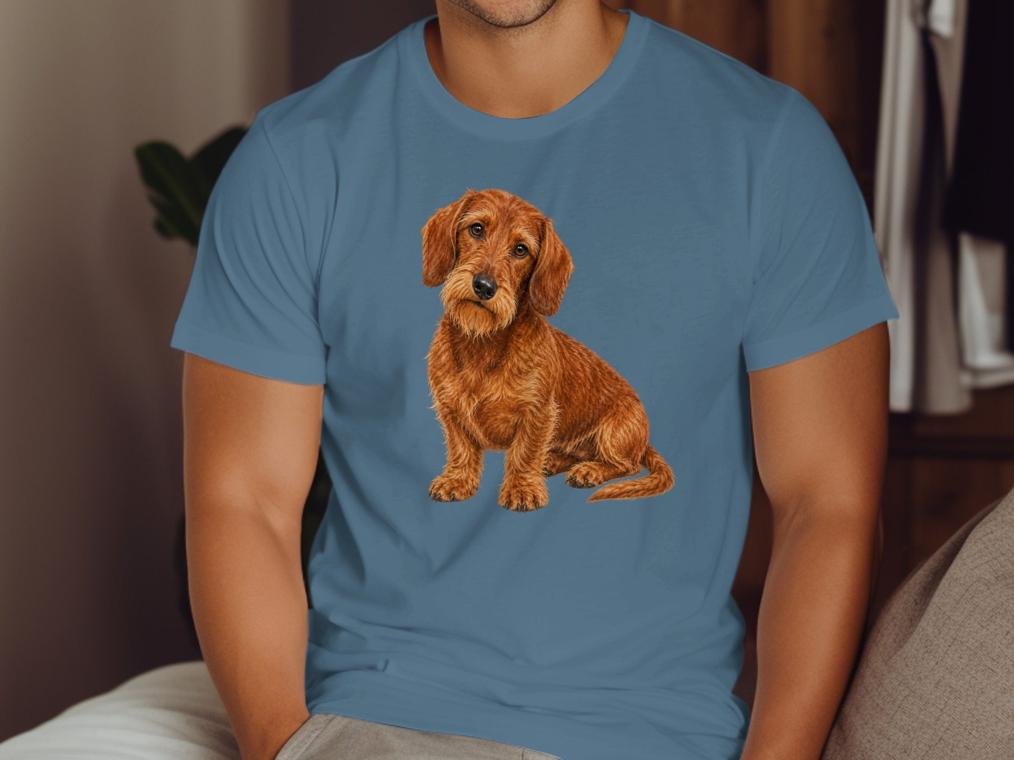 Watercolor illustration of a wirehaired dachshund sitting on a blue t-shirt.