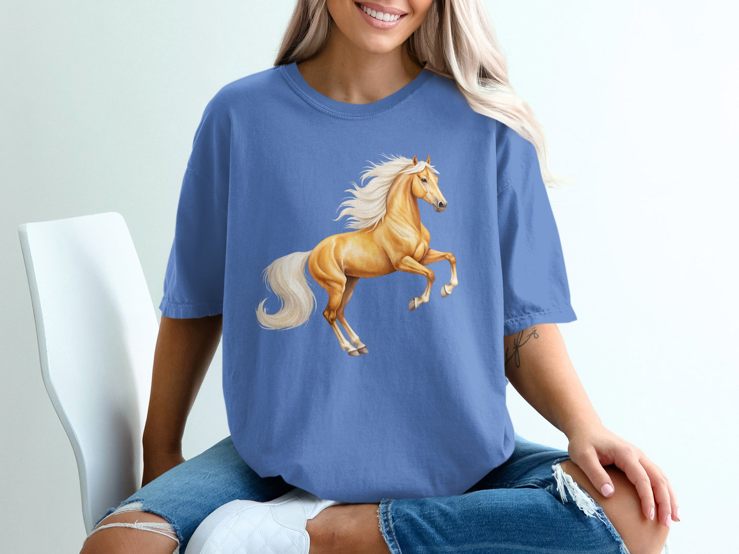Cream horse rearing with flowing mane and tail on blue t-shirt.