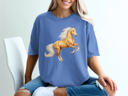 Cream horse rearing with flowing mane and tail on blue t-shirt.