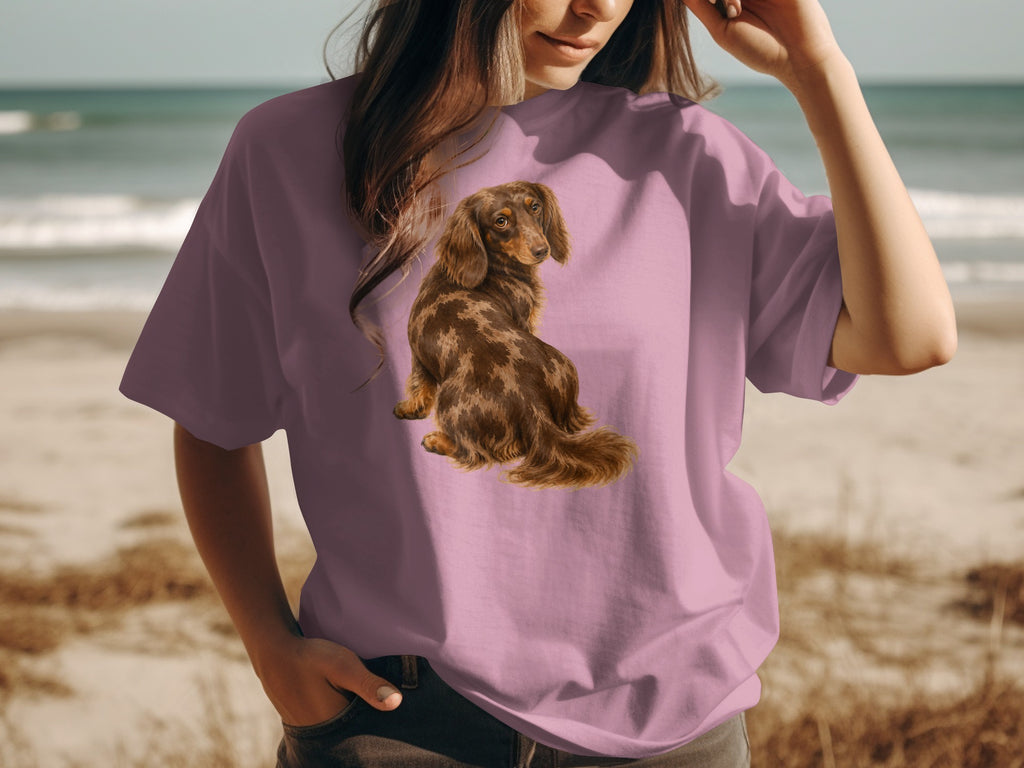 Dachshund illustration on a pink t-shirt worn by a person at the beach.