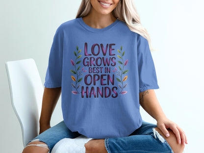 Purple t-shirt with text "LOVE GROWS BEST IN OPEN HANDS" and floral accents.