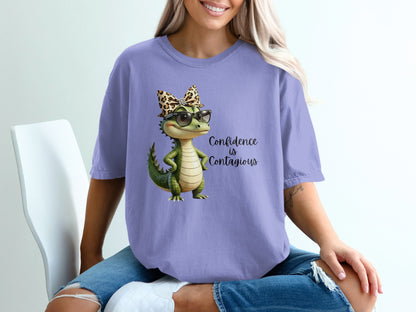 Lavender t-shirt with a cartoon alligator wearing glasses and a leopard print bow.