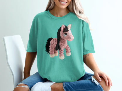 Crocheted pink horse graphic on a teal t-shirt.