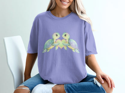 Two cartoon turtles with a heart, printed on a purple t-shirt.