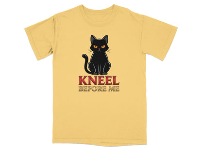 Black cat with red eyes and text "KNEEL BEFORE ME" on a yellow t-shirt.