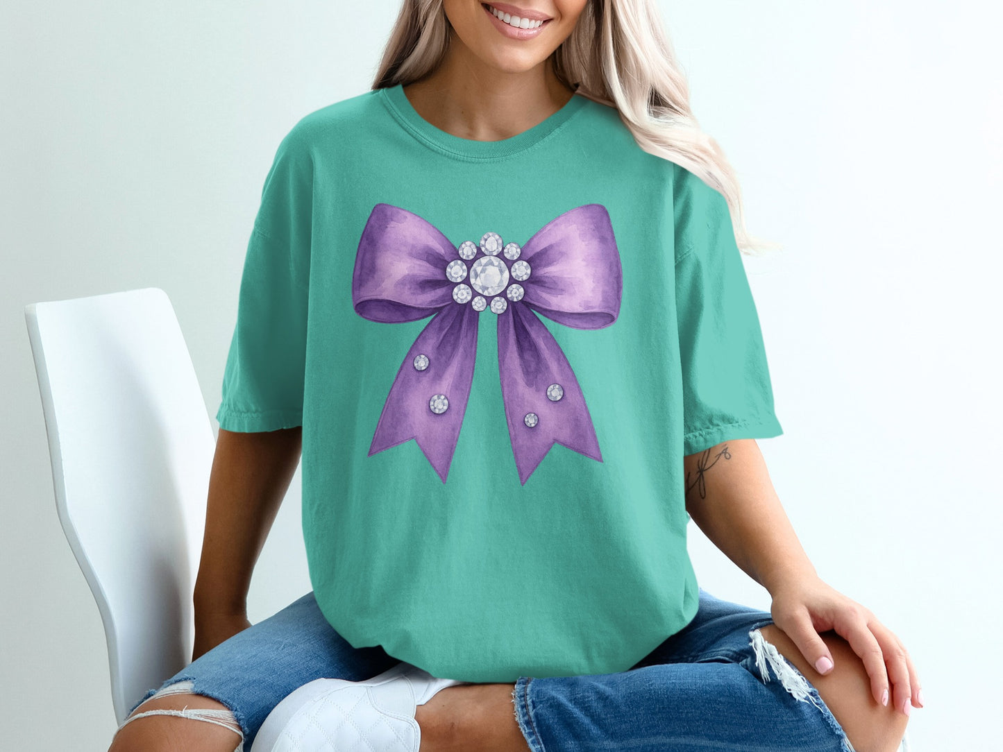 Teal t-shirt with a large purple bow embellished with rhinestones.