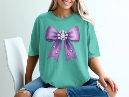 Teal t-shirt with a large purple bow embellished with rhinestones.