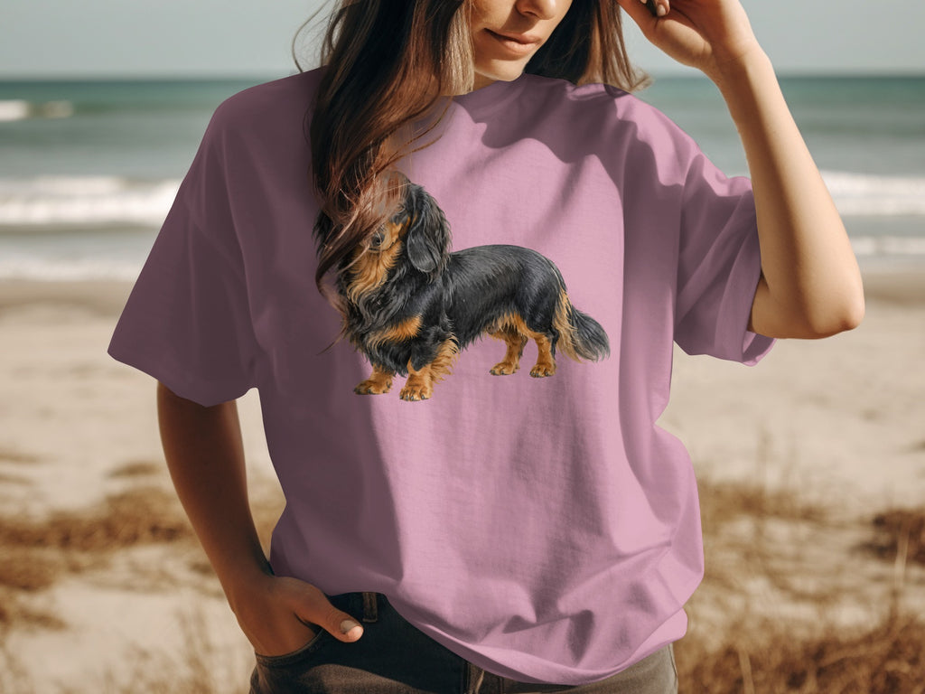 Long-haired dachshund illustration on a pink t-shirt worn by a person at the beach.