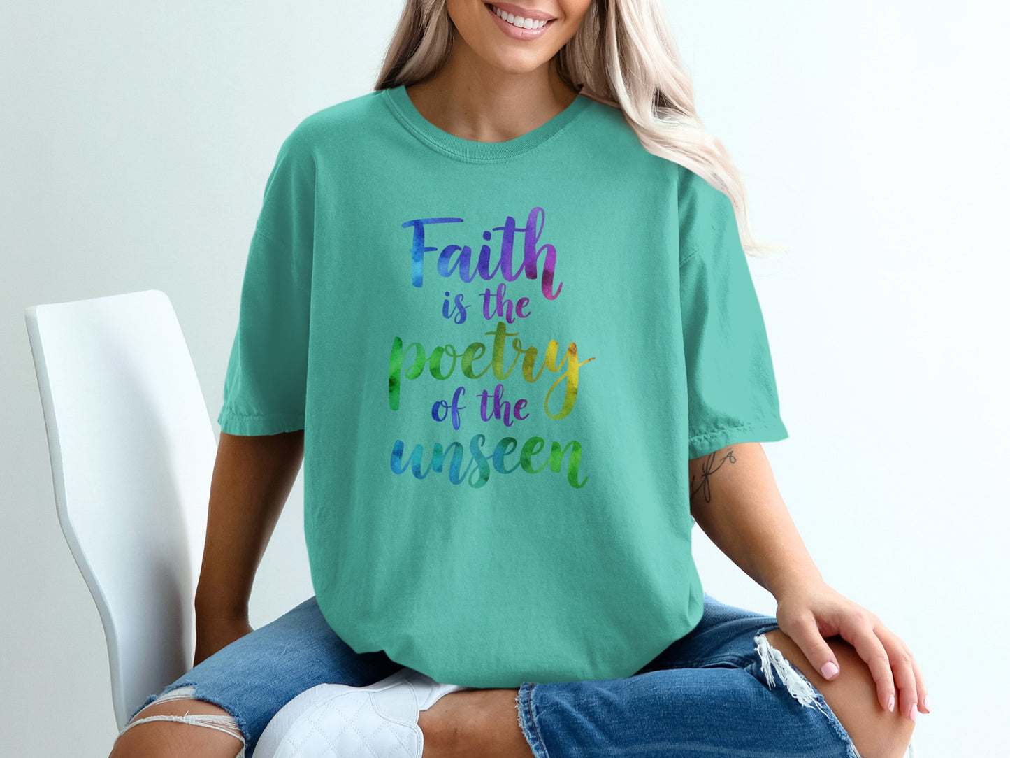 Teal t-shirt with "Faith is the poetry of the unseen" in rainbow lettering.