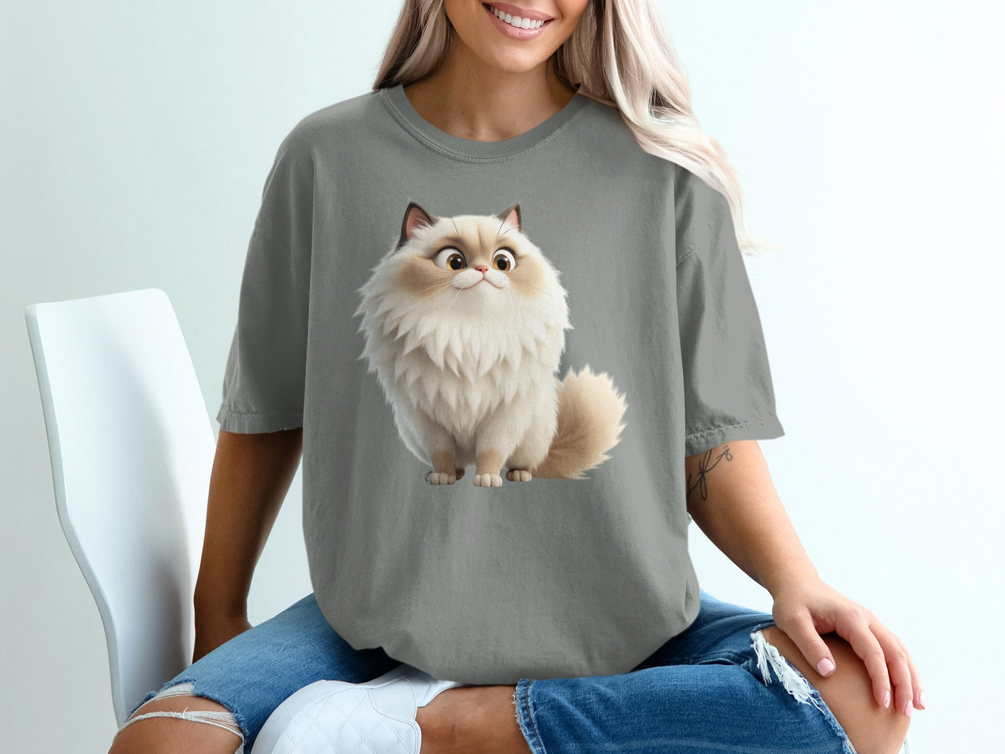 Fluffy cartoon cat illustration on a gray t-shirt worn by a woman.