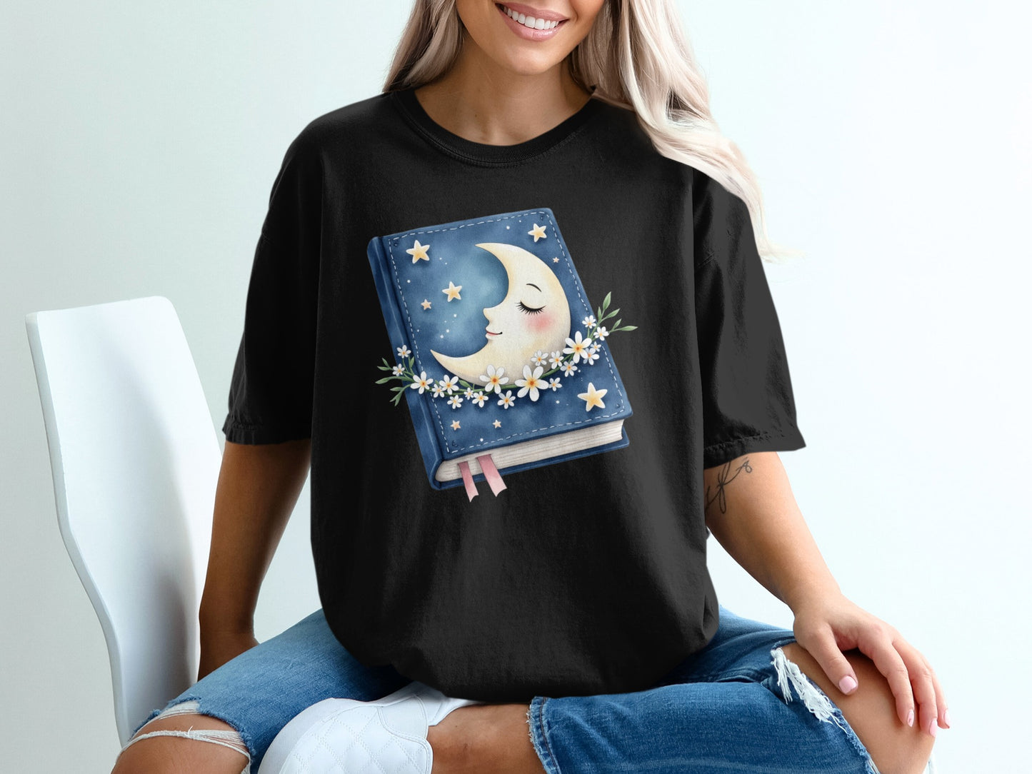 Black t-shirt with crescent moon, stars, and floral book graphic.