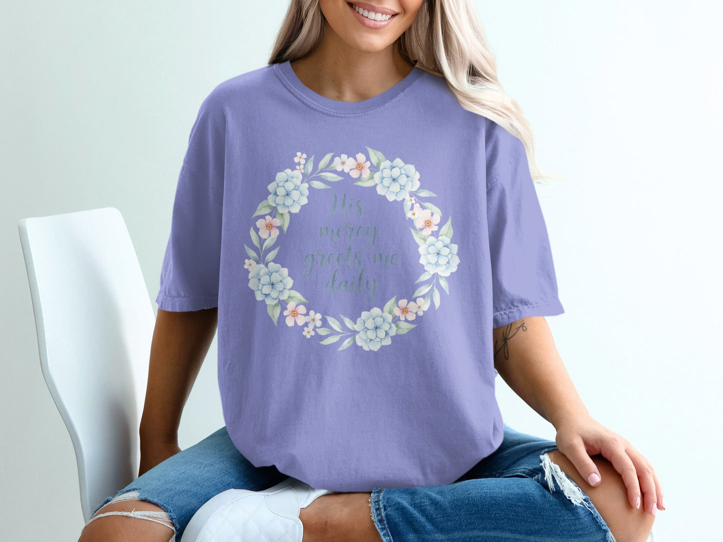 Purple t-shirt with floral wreath and "His mercy greets me daily" text.