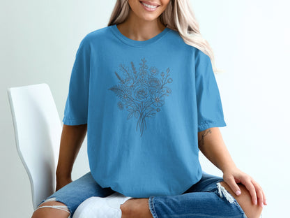 Woman wearing a blue t-shirt with a floral line drawing design.