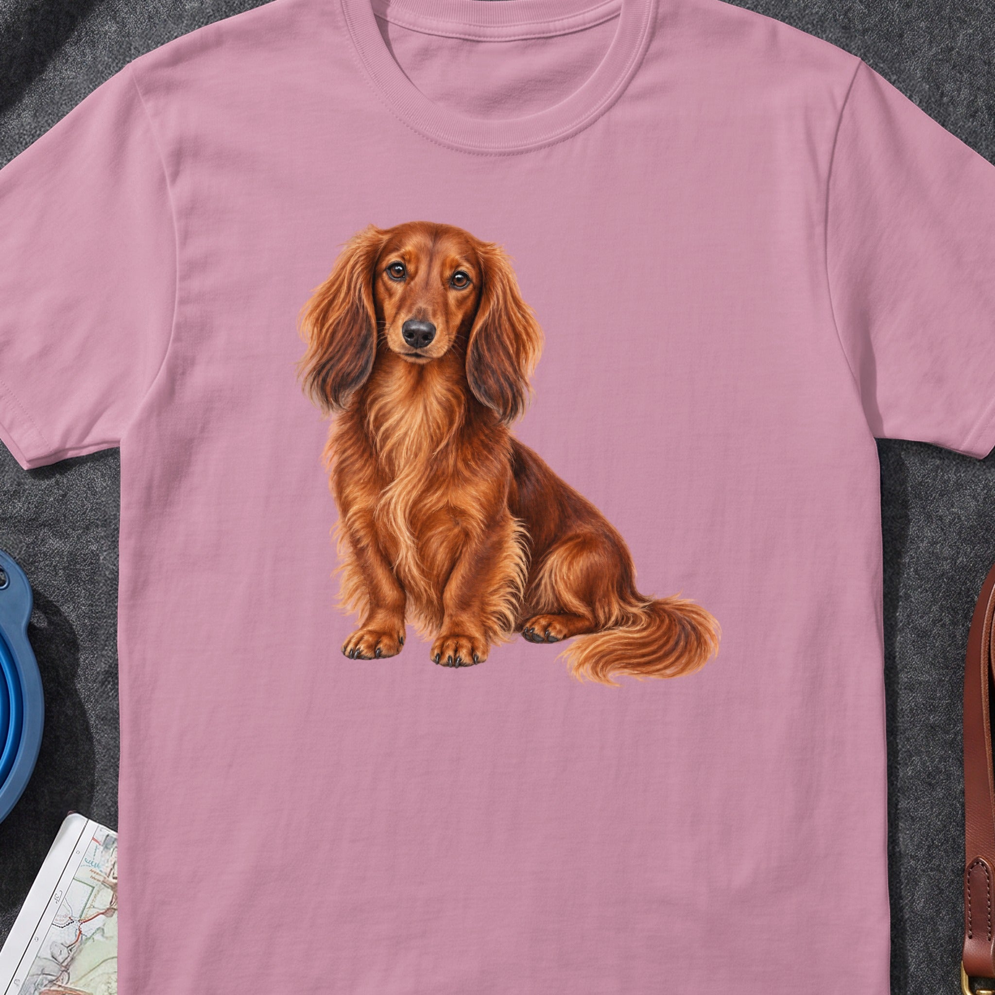 Pink t-shirt with a detailed illustration of a long-haired, reddish-brown dachshund.
