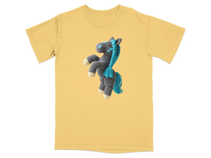 Crocheted gray horse with blue mane and tail on yellow t-shirt.
