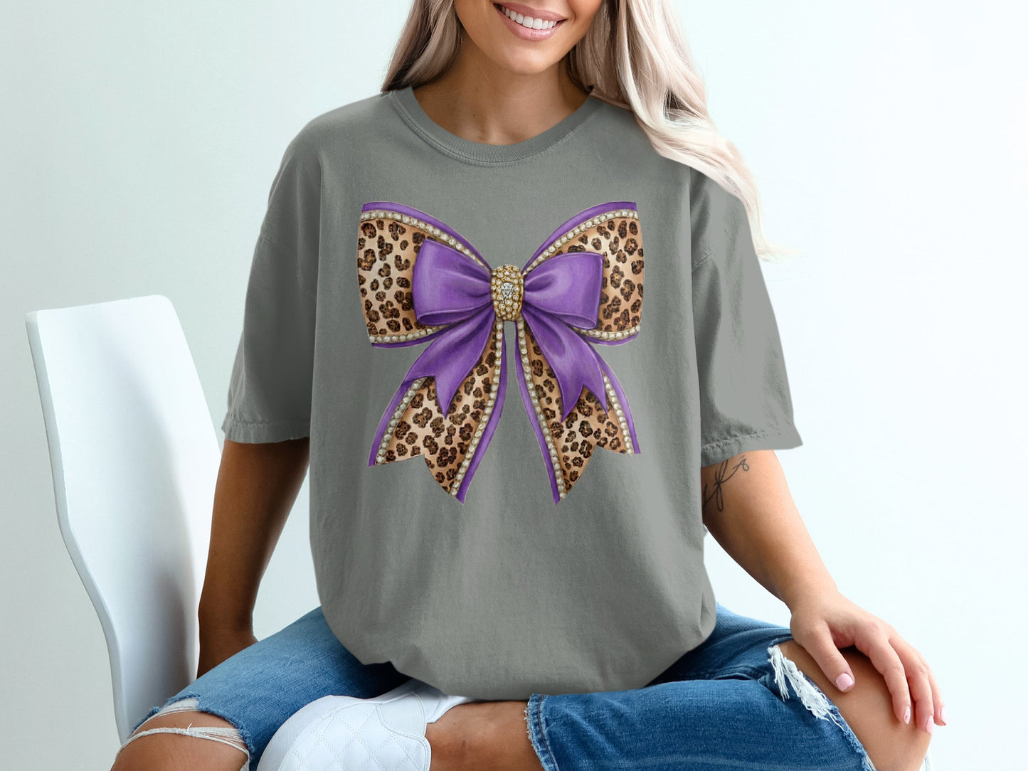 Purple glittery bow with leopard print accents on a gray t-shirt.
