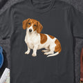 Dachshund with brown and white markings sitting on a dark grey t-shirt.