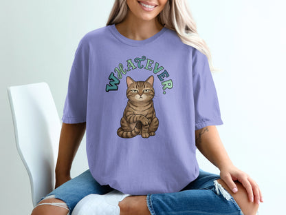 Cat wearing a t-shirt with "Whatever" text, sitting on a chair.