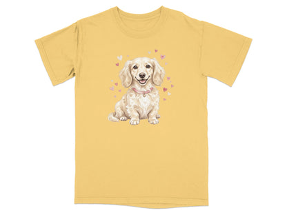Cream dachshund wearing a pink collar with hearts, on a yellow t-shirt.