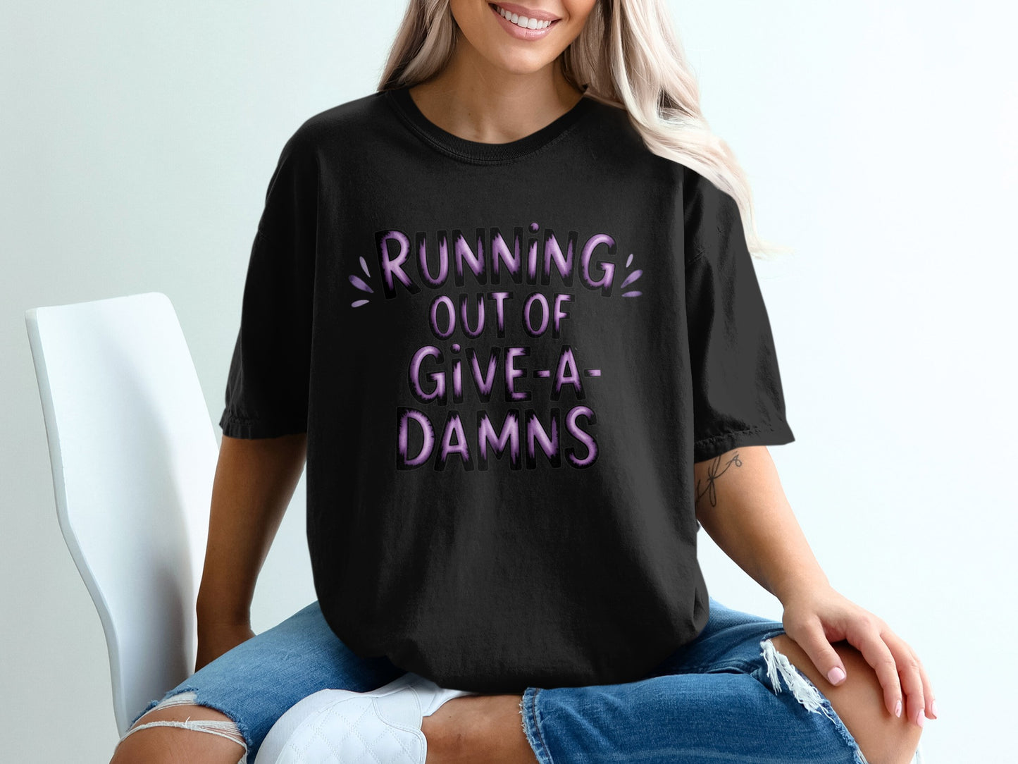 Black t-shirt with "RUNNING OUT OF GIVE-A-DAMS" text in purple.