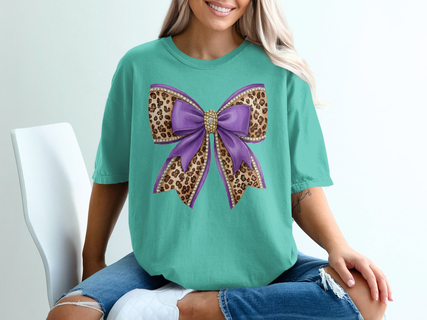 Teal t-shirt with a large purple bow decorated with a leopard print pattern.