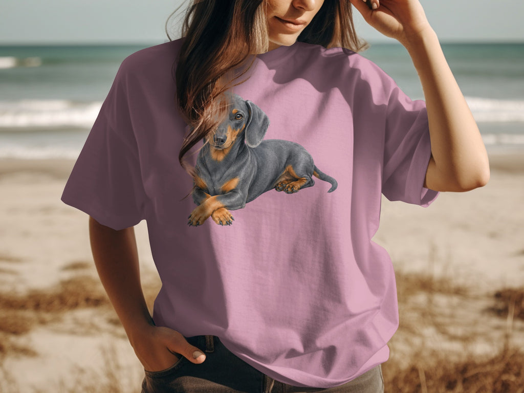 Dachshund illustration on a pink t-shirt worn by a person on the beach.