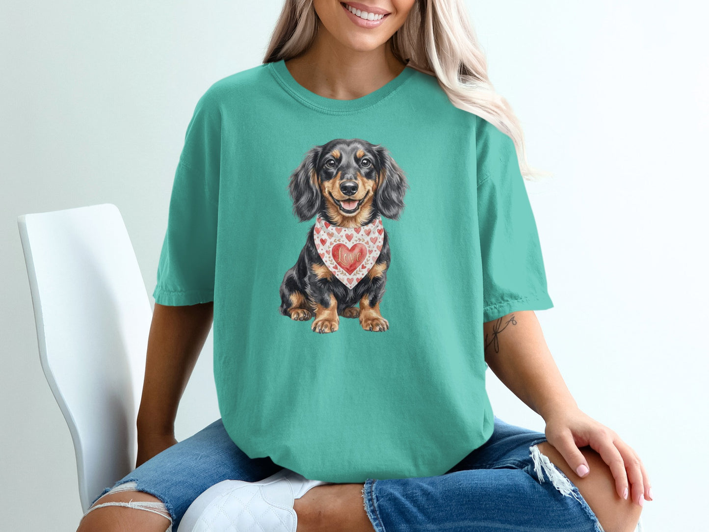 Dachshund wearing a heart bandana, printed on a teal t-shirt.