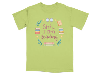 Green t-shirt with "Shh I Am Reading" text surrounded by books and greenery.