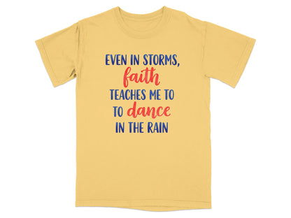 Yellow t-shirt with red and blue text: "Even in storms, faith teaches me to dance in the rain."