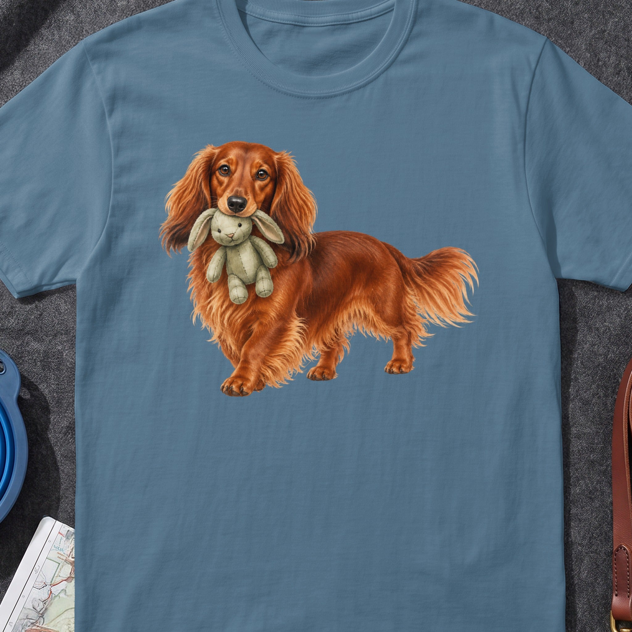 Long-haired dachshund holding a stuffed bunny on a blue t-shirt.