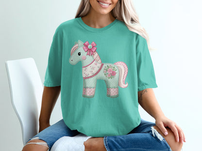 Teal t-shirt with a decorative patchwork horse wearing a pink bow.