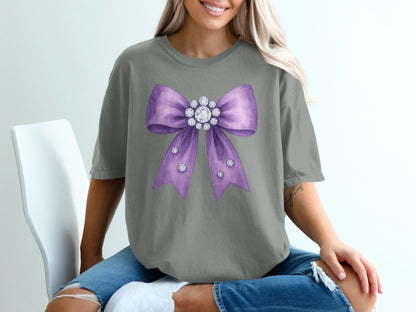 Grey t-shirt with a large purple bow adorned with rhinestones.