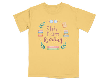 Yellow t-shirt with "Shh... I am Reading" text and stacked books illustration.
