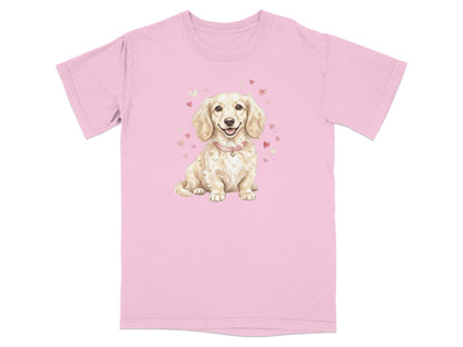 Cream dachshund wearing a pink collar and heart necklace on a pink t-shirt.
