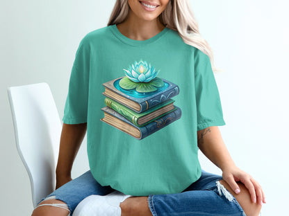 Teal t-shirt with stacked books, lotus flower, and water illustration.