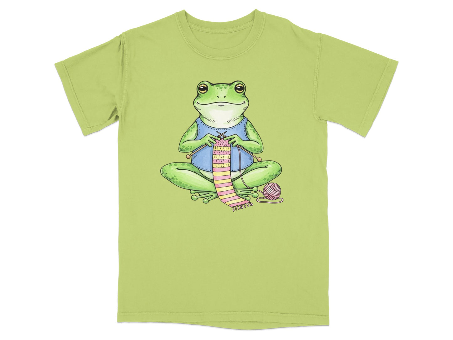 Green t-shirt with illustration of a frog knitting a pink and green striped scarf.
