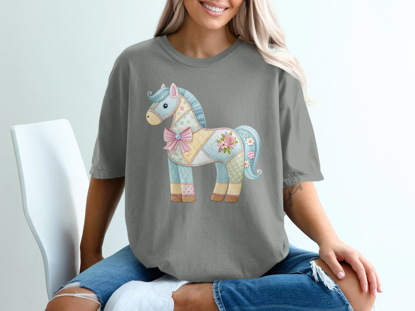 Grey t-shirt featuring a pastel patchwork horse with a pink bow and floral accents.