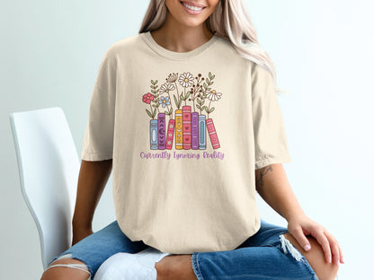 Cream t-shirt with books and flowers graphic and "Currently Ignoring Reality" text.