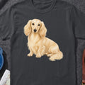 Cream-colored long-haired dachshund sitting on a dark gray t-shirt.