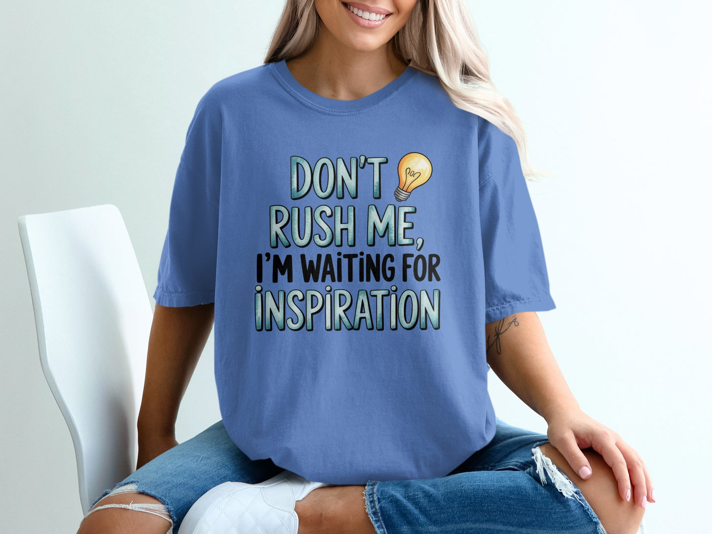 Blue t-shirt with "DON'T RUSH ME, I'M WAITING FOR INSPIRATION" text and lightbulb graphic.