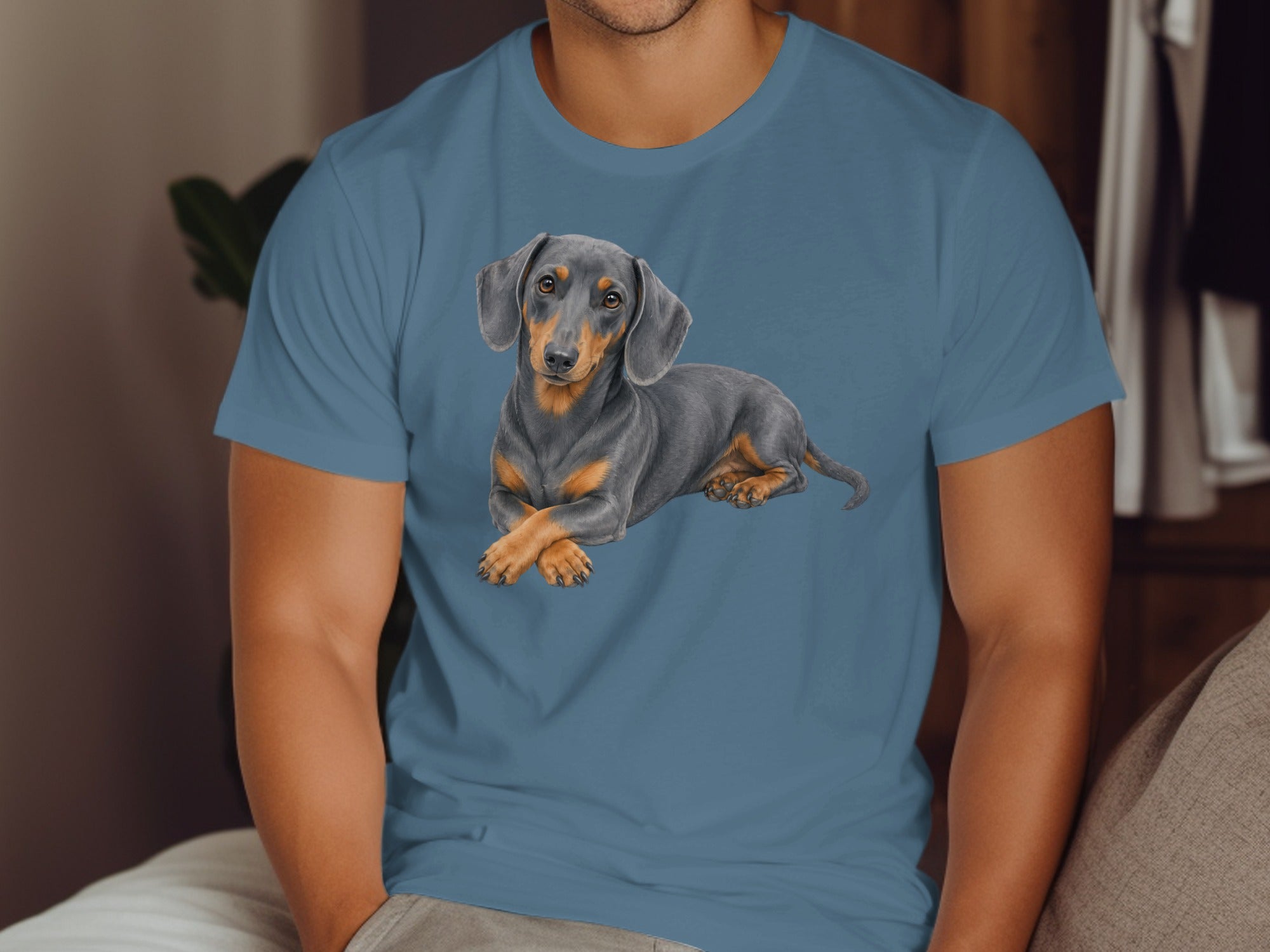 Dachshund dog lying down with paws crossed on a blue t-shirt.