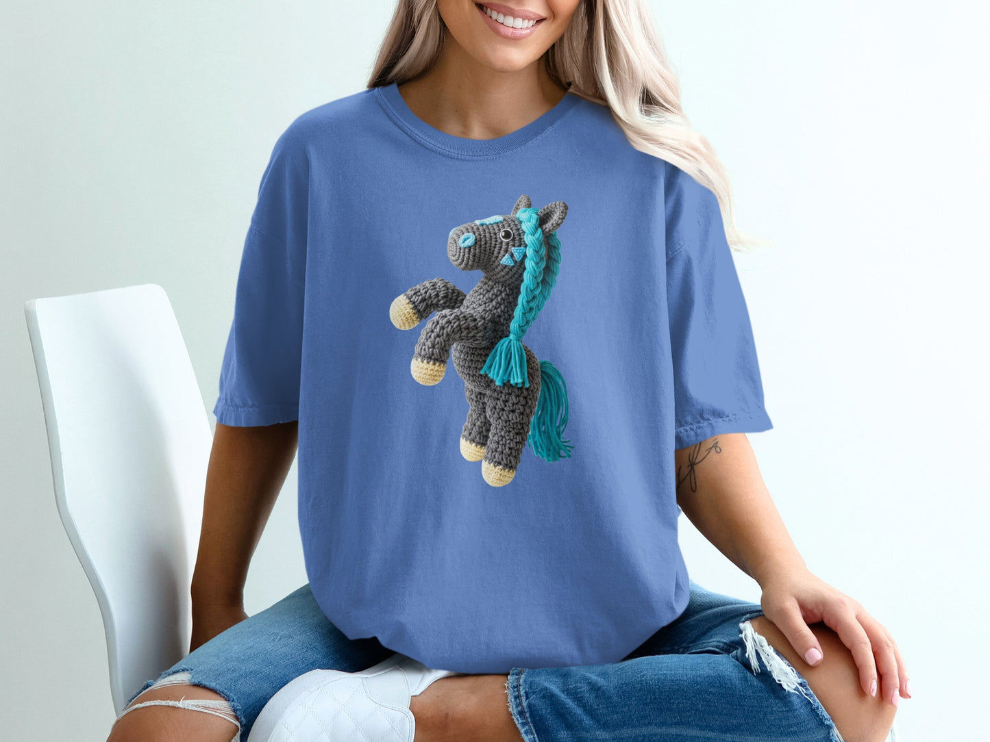 Crocheted horse graphic on a blue t-shirt worn by a woman.