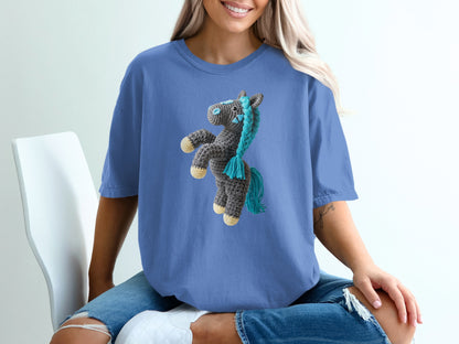 Crocheted horse graphic on a blue t-shirt worn by a woman.