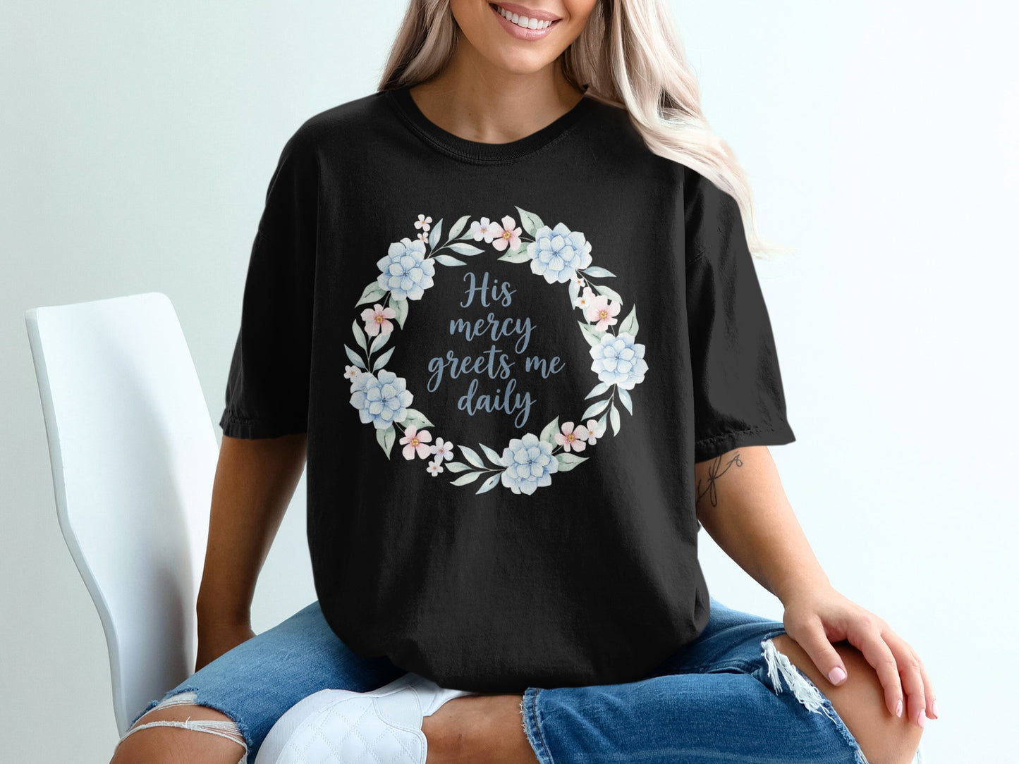 Black t-shirt with a floral wreath graphic and text "His mercy greets me daily."