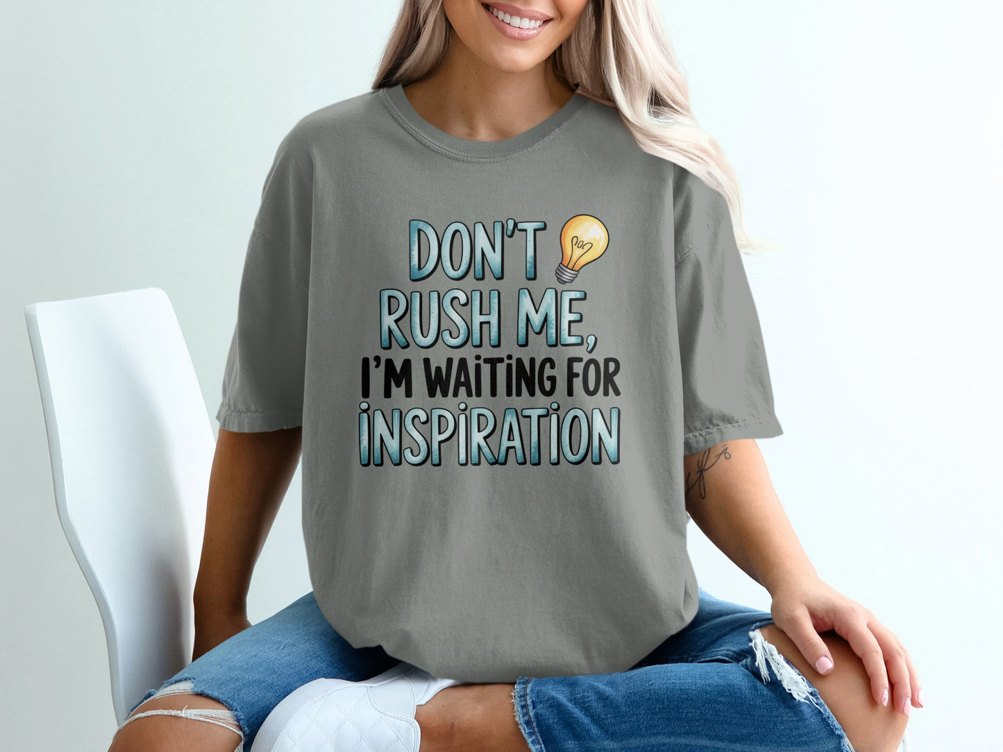 Gray t-shirt with "DON'T RUSH ME, I'M WAITING FOR INSPIRATION" and a lightbulb.
