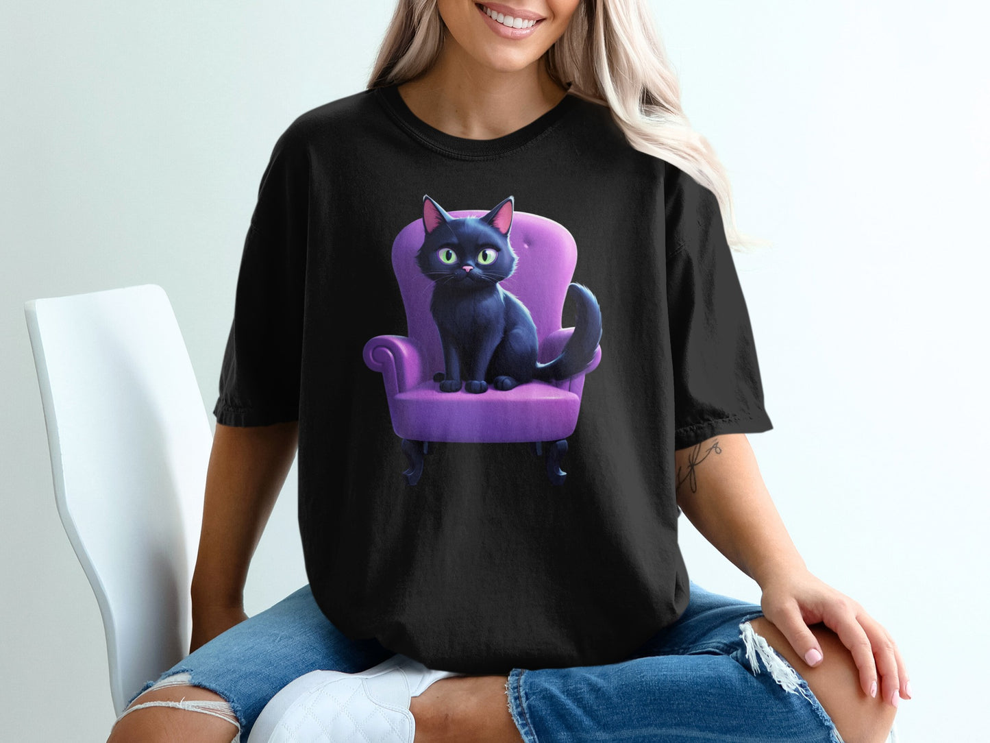Black t-shirt featuring a cartoon black cat sitting on a purple chair.