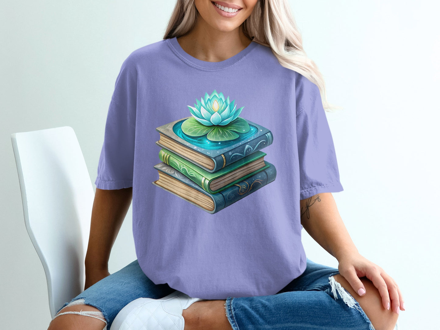 Stack of books with a lotus flower on top, on a purple t-shirt.