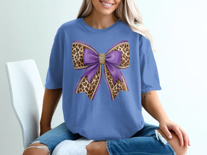 Purple bow with leopard print and rhinestones on a blue t-shirt.