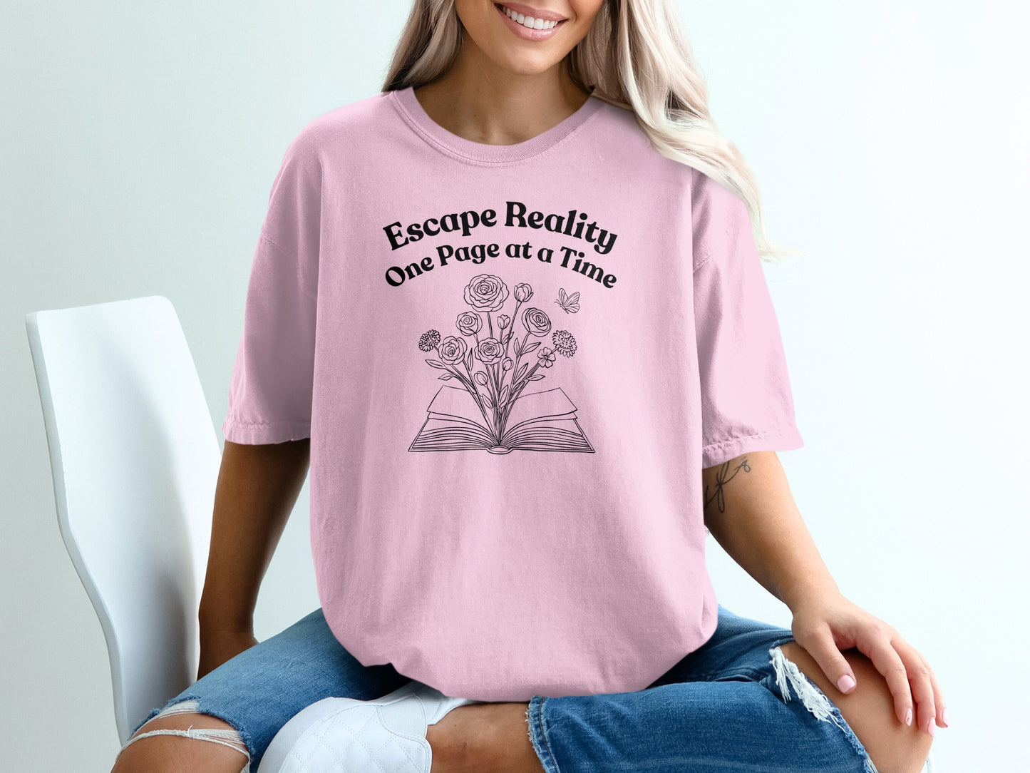 Pink t-shirt with "Escape Reality One Page at a Time" and a book with flowers.